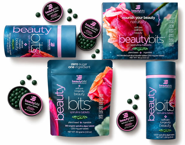 Beauty Bits skincare supplement products including a box, pouch, and tub with matching round jars, arranged on a white background with scattered dark green tablets.